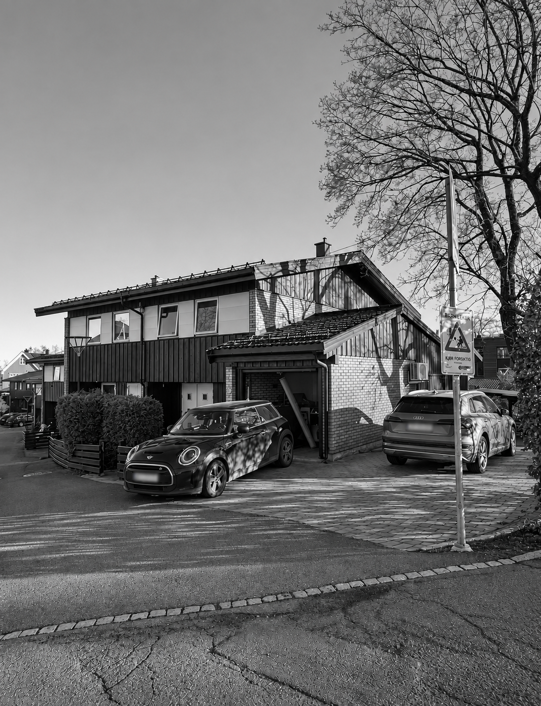 Ørakerstien i svart-hvitt sett fra gatehjørnet med garasjen og innkjørselen