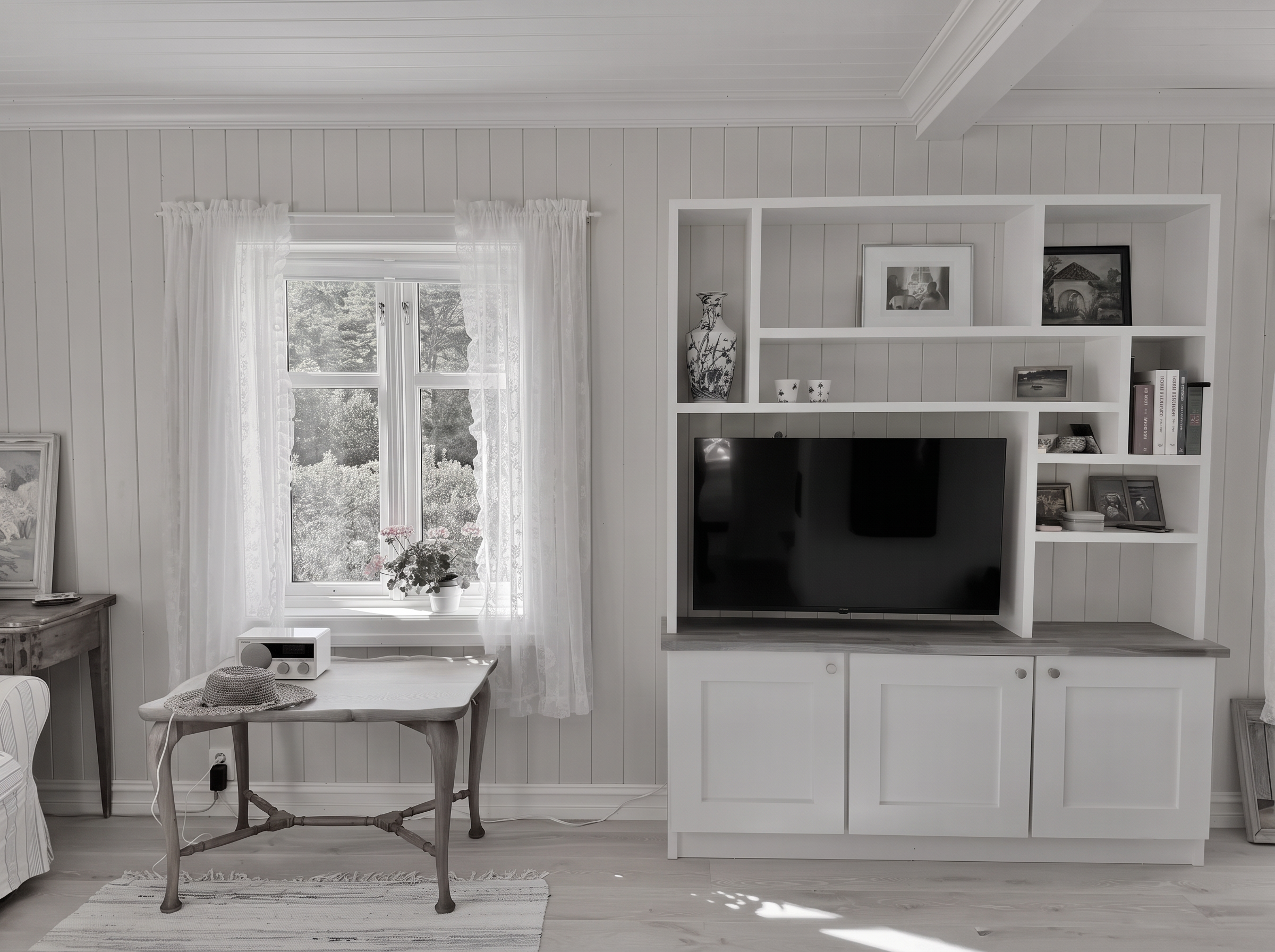 Stue i svart-hvitt med panel, blondegardiner og innebygd reol